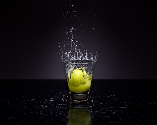 Hands holding a glass of fresh water with lemon