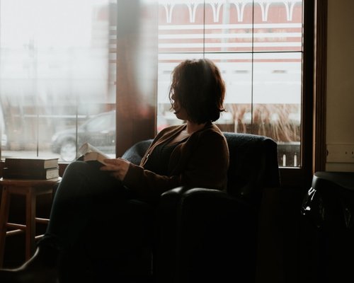 Woman reading a book in a cozy chair by the window